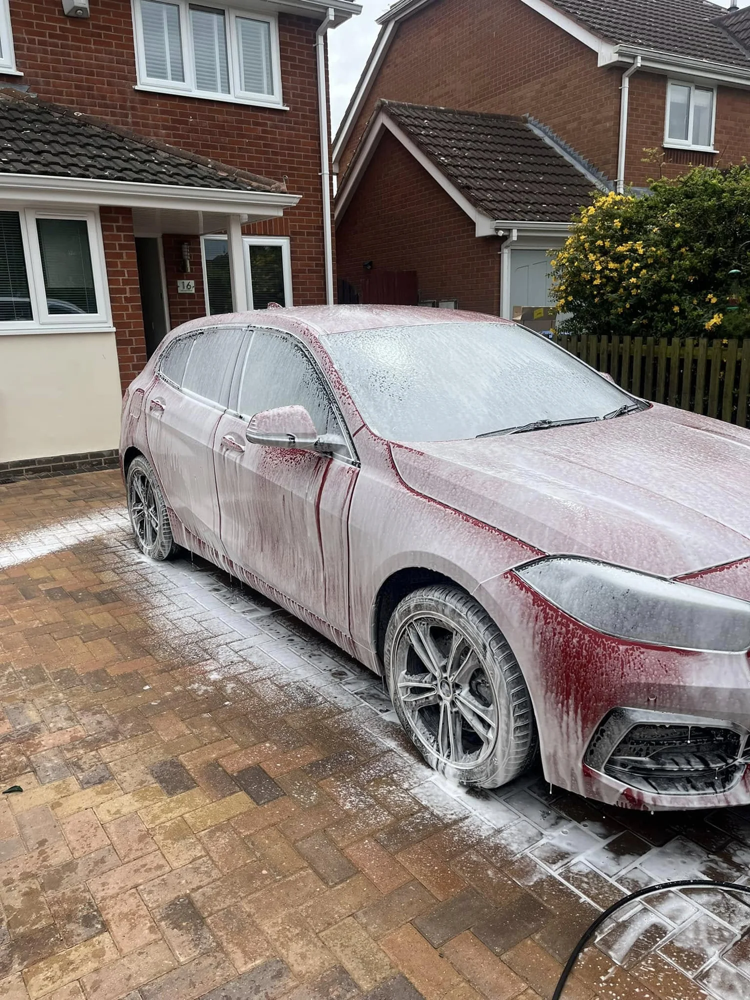 A vehicle covered in snow foam during a mobile valet at home
