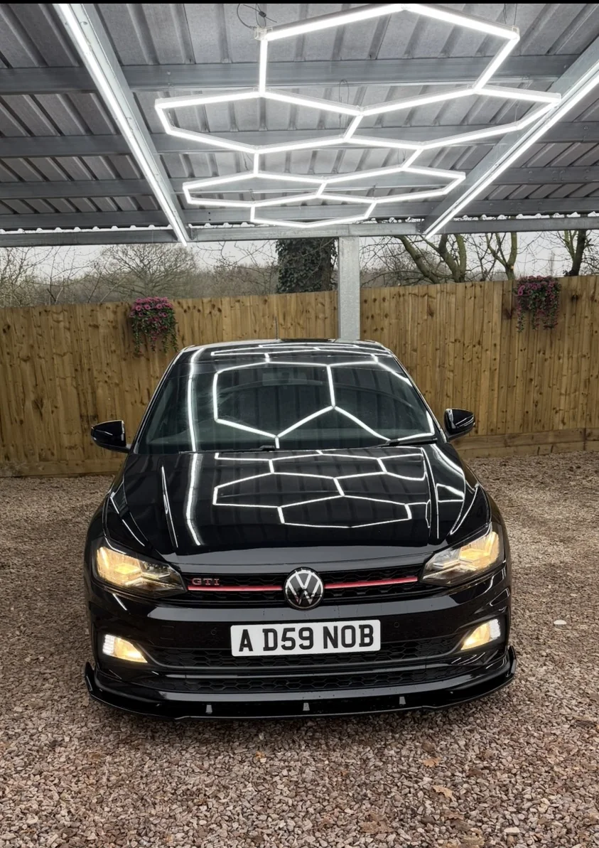 Black Volkswagen GTI beneath detailing lights