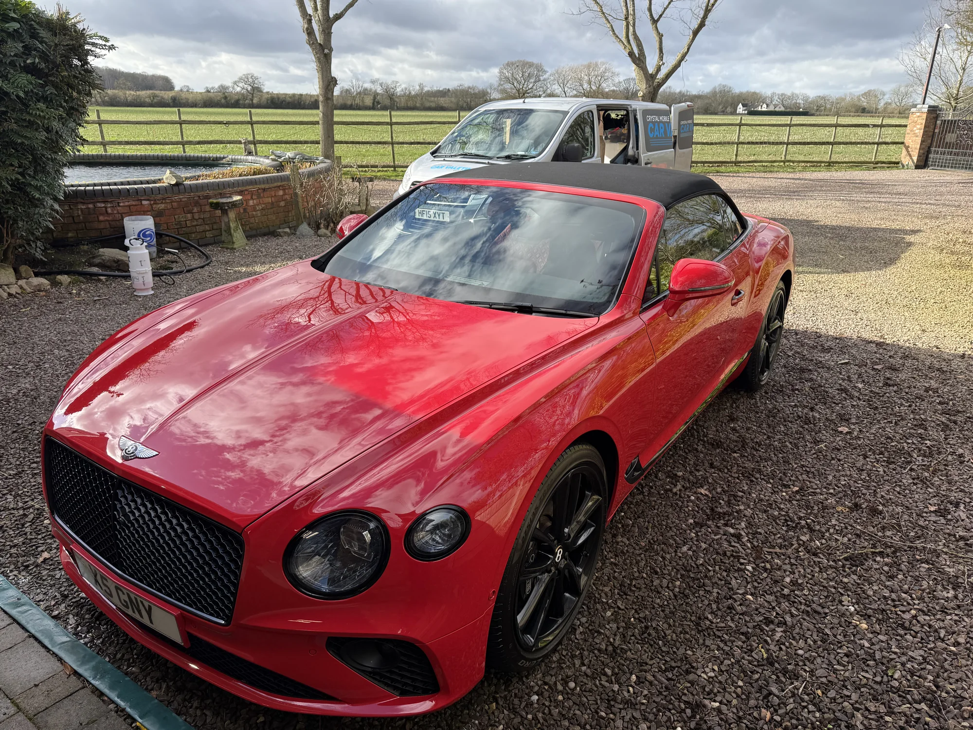 A professionally cleaned red Bentley with a Crystal Mobile Car Valeting van in the background
