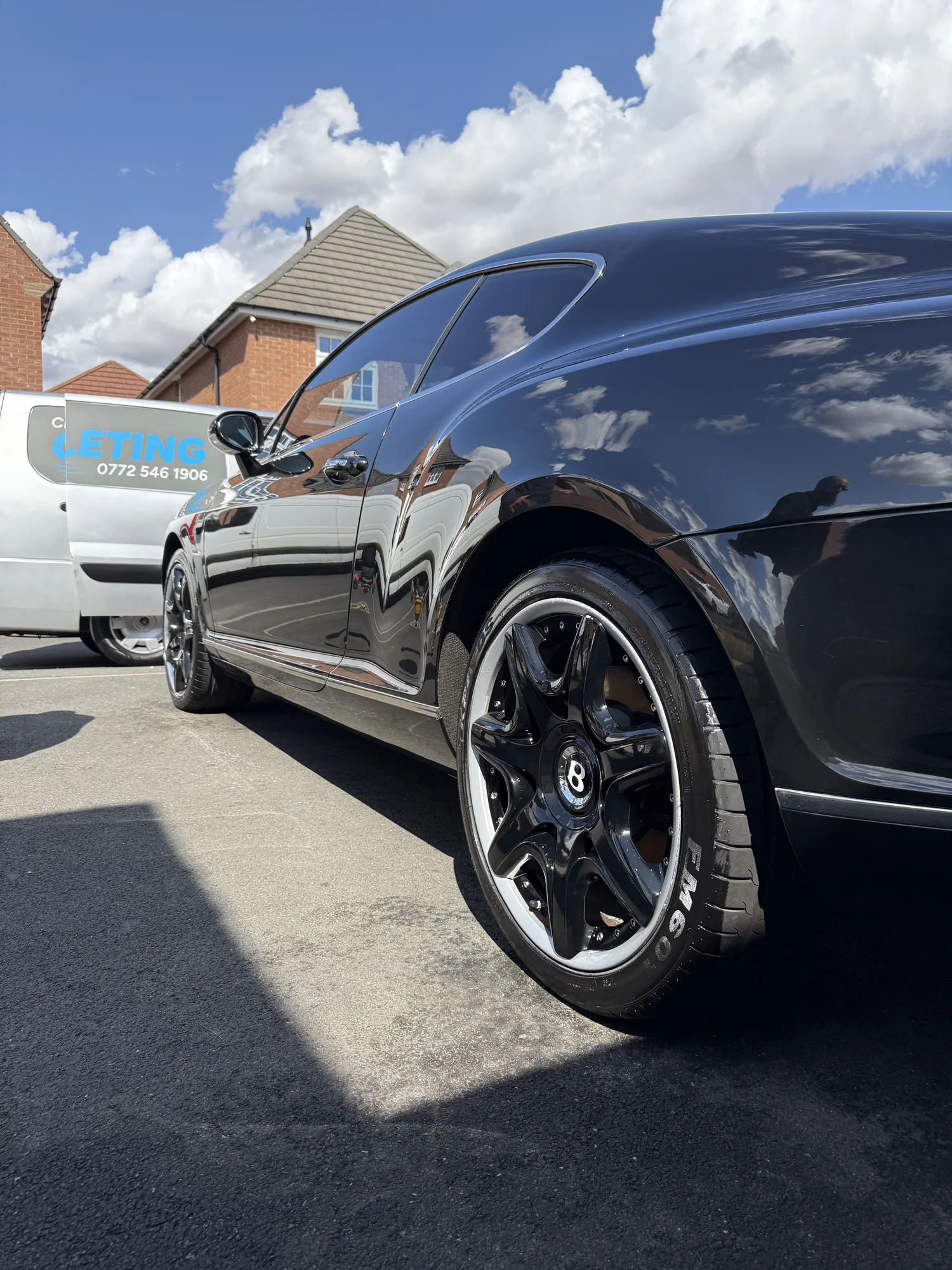 A freshly valeted black Bentley with the Crystal Mobile Car Valeting van nearby